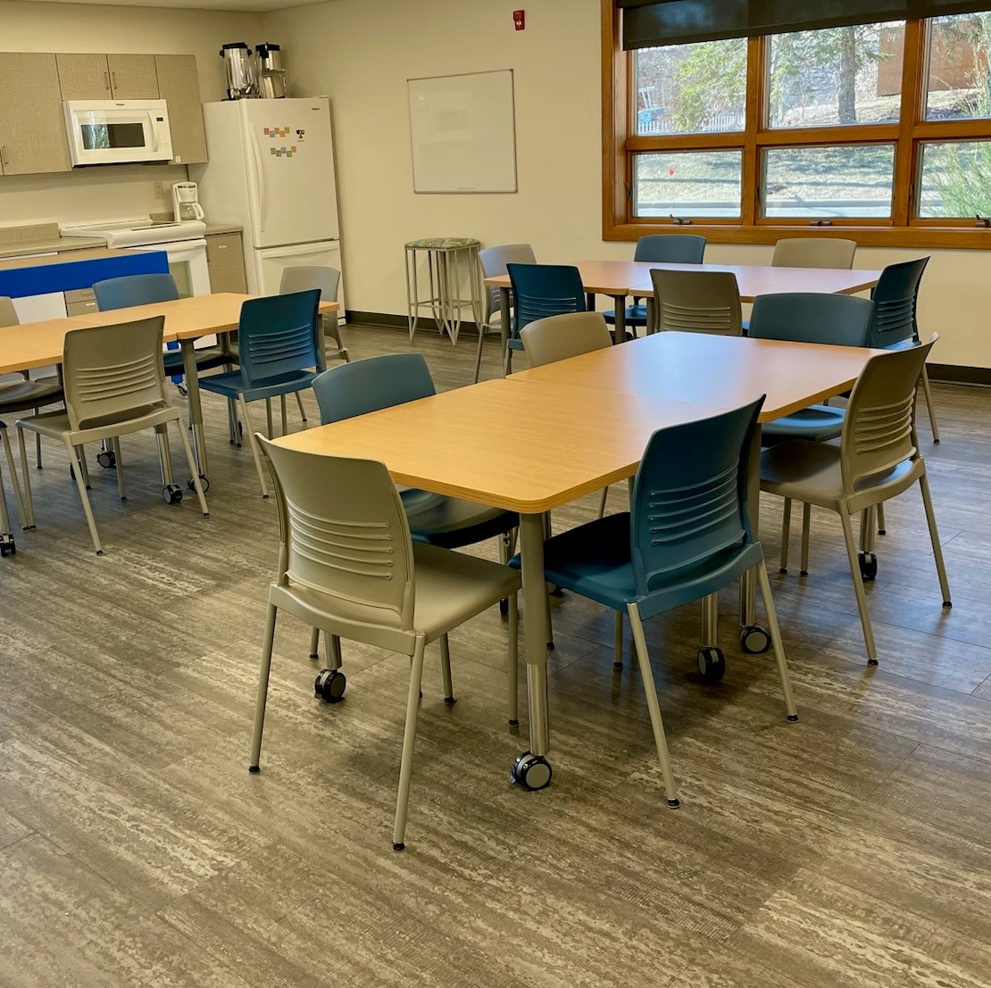 The Maker Space, with tables and chairs, a white board, a fridge, microwave, oven, sink, and coffee maker